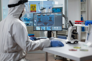 Biologist researcher wearing protective medical equipment while working at coronavirus prevention vaccine in microbiological hospital laboratory. Scientist man analyzing virus expertise