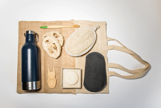 Art&iacute;culos zero waste sobre una bolsa tote bag. Botella de agua de acero inoxidable, spork, esponja de lufa, compresa menstrual reutilizable, champ&uacute; s&oacute;lido, cepillo de dientes de bamb&uacute;