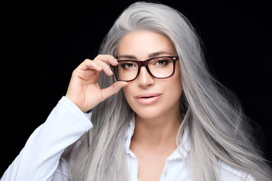 Successful confident mature businesswoman with long grey hair wearing glasses in a close up portrait