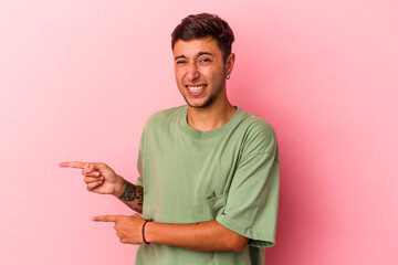 Young caucasian man with tattoos isolated on yellow background  shocked pointing with index fingers to a copy space.