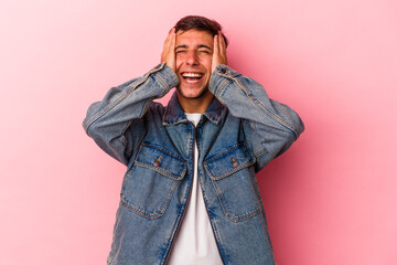 Fototapeta premium Young caucasian man with tattoos isolated on yellow background laughs joyfully keeping hands on head. Happiness concept.