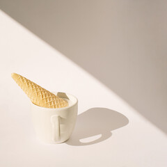 cup of coffee with ice cream cone upside down in it.white background with soft shadows.end of summer and autumn concept idea