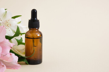 Amber glass bottle on a neutral background with a lily flowers. copy space. Cosmetic, skin care concept