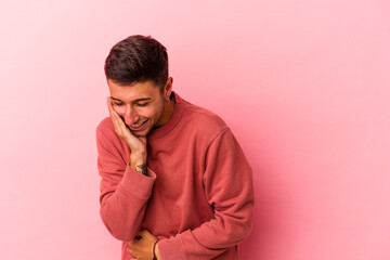 Young caucasian man with tattoos isolated on yellow background  laughs happily and has fun keeping...