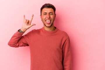 Young caucasian man with tattoos isolated on yellow background  showing rock gesture with fingers