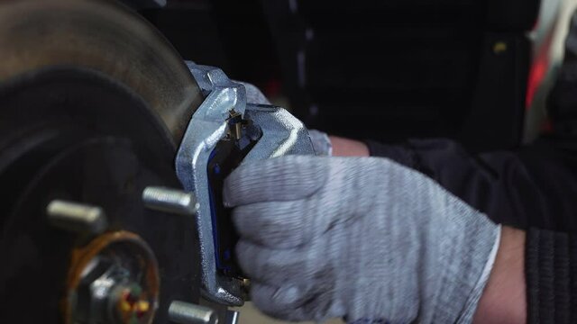 The car mechanic unscrews the brake pads. Close-up
