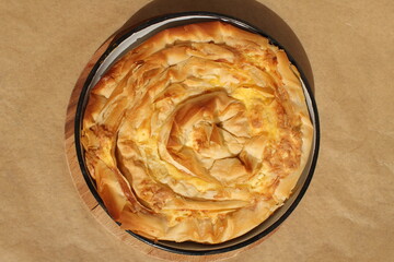 Child hand touching Bulgarian traditional baked dish with cheese, eggs and filo dough called banitza or banitsa
