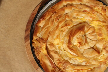 Child hand touching Bulgarian traditional baked dish with cheese, eggs and filo dough called...