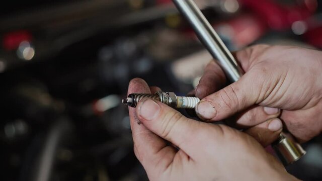 An auto mechanic replaces the spark plugs in the car