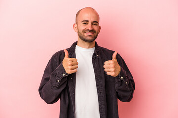 Young caucasian bald man isolated on pink background  smiling and raising thumb up