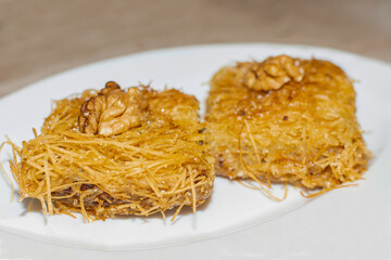 Kadaif (Kadayif) is a traditional Middle Eastern dessert made of thin noodles like pastry, and soaked on sweet, sugar based syrup and decorated with nuts and other pistachio.