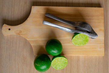 green lime with a lime press on a wooden cutting board