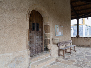 Puerta y banco en la fachada de la Iglesia de San Julián de Viñon, pueblo de Cantabria, España, verano de 2020