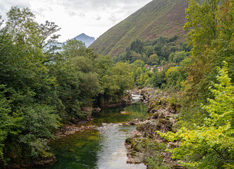 Fototapeta na wymiar Vistas del Río Sella, rodeado de vegetación y montañas al fondo, a su paso por el pueblo de Tornín en Cantabria, verano de 2020, España