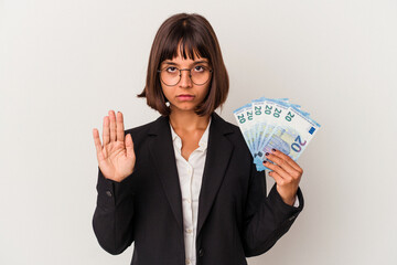 Young mixed race business woman holding a banknotes isolated on white background standing with outstretched hand showing stop sign, preventing you.