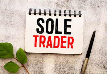 SOLE TRADER, text on white notepad paper on wood table