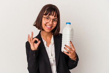 Young mixed race business woman holding a milk bottle isolated on white background cheerful and...