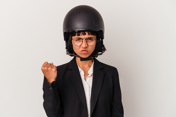 Young mixed race business woman wearing a motorbike helmet isolated showing fist to camera, aggressive facial expression.