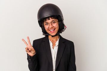 Young mixed race business woman wearing a motorbike helmet isolated joyful and carefree showing a peace symbol with fingers.