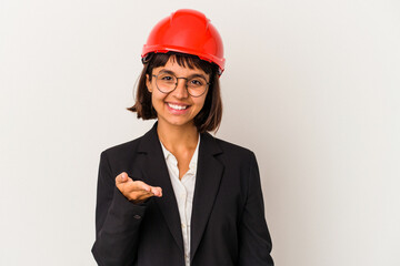 Young architect woman with red helmet isolated on white background stretching hand at camera in greeting gesture.