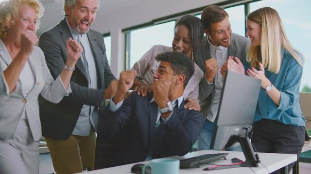 Mixed-races Team Of Office Workers Cheering In Front Of Computer Screen And Celebrating Successful Work Finish Of Project. Multiethnic Male And Female Business People Applauding As Having Great Result