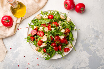 Salad with mozzarella, tomatoes and arugula on white plate top view