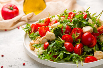 Salad with mozzarella, tomatoes and arugula on white plate