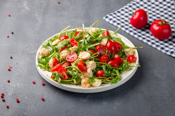 Salad with mozzarella, tomatoes and arugula on white plate