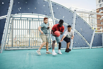 African-American father holding basketball while fighting for it while playing with sons on sports...