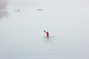 Fototapeta na wymiar Kayak riding on river. Man in boat on water. Kayaking in fog