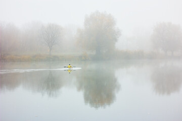 Obraz na płótnie Canvas Kayak riding. Man in boat and trees on river bank. Kayaking in fog