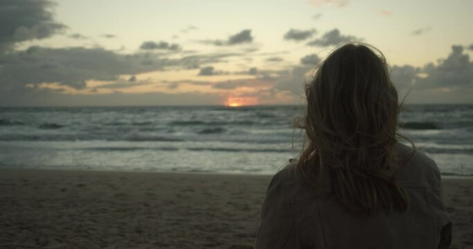 Blonde girl in front of the sunset on a windy day in slow motion