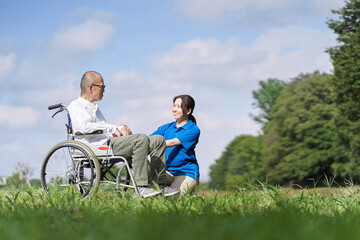 芝生で会話をする高齢者と介護士