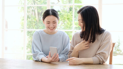 Obraz premium スマートフォンを一緒に使う母と娘