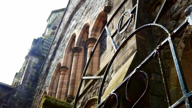 Weathered freemason lodge rusted gate entrance looking up at stone wall window arches dolly left