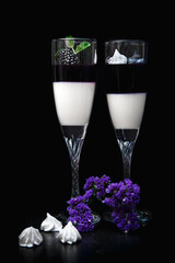 Blackberry panna cotta in glasses on a black background.