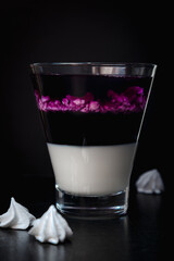 Blackberry panna cotta in glasses on a black background.