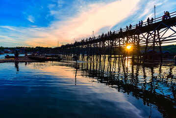 Fototapeta premium Beautiful sunset scene at old an long wooden bridge at Sangklaburi,Kanchanaburi province, Thailand