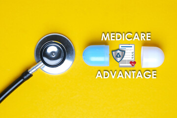 A picture of stethoscope with fake capsule, medicare advantage word, tablet, money shield and heart. - obrazy, fototapety, plakaty