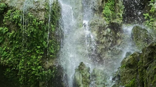 Magical mountain waterfall, crystal water, large stones overgrown with moss. The waterfall with the crystal clear water that flows quickly. slow motion. 4K. B ROOL. Camera tilt down from up. 3.