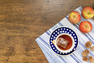 Hot tea in a polish pottery tea cup with a striped linen kitchen towel on a wooden countertop. 