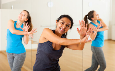 Portrait of dancing latin american woman practicing vigorous swing during group training in dance...