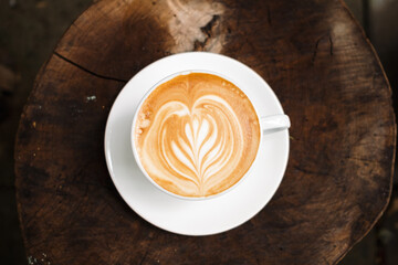 Latte art coffee on wooden table in coffee shop