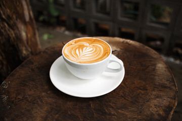 Latte art coffee on wooden table in coffee shop