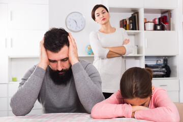 Young mother lecturing her husband and daughter for disobedience at home