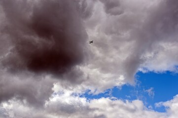 A plane is flying high in the sky in the clouds