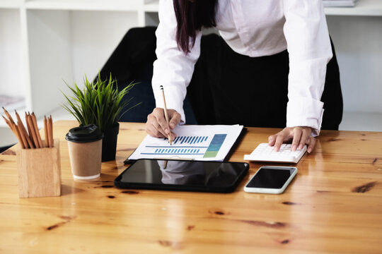 A businesswoman using pen point to chart document is researching earnings affected by the coronavirus pandemic to adjust her market strategy.