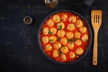 Meatballs in tomato sauce in a frying pan on dark background. Top view, flat lay.