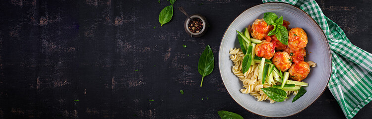 Italian pasta. Fusilli with meatballs, cucumber and basil on dark background. Dinner. Slow food concept. Top view, banner