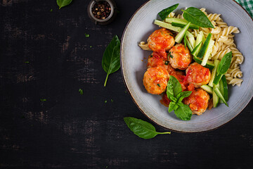 Italian pasta. Fusilli with meatballs, cucumber and basil on dark background. Dinner. Slow food concept. Top view, flat lay